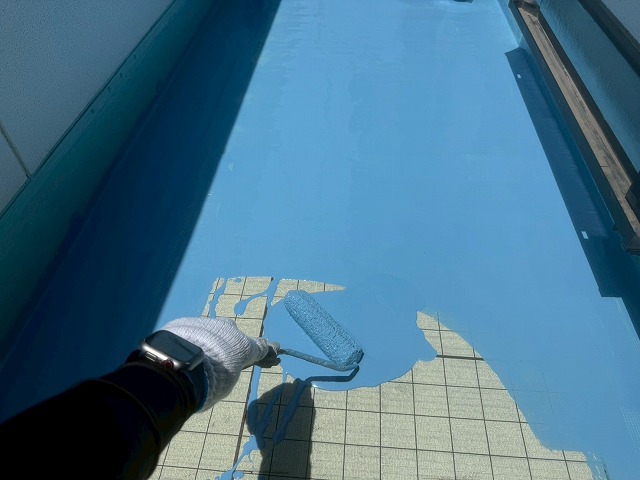 名古屋市守山区で経年劣化したFRP防水の上からウレタン防水通気緩衝工法を実施、防水膜を形成しトップコートで施工を完了する様子