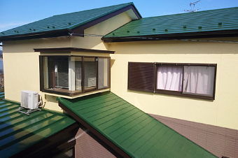 深い緑色の屋根にクリームイエローの外壁で可愛い印象の外観に